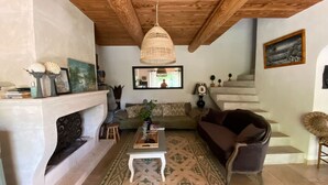 A cozy living room with a fireplace, a woven ceiling light, a patterned rug, and a staircase leading upstairs. - Charming Villa With AC in Alpilles (Paradou)