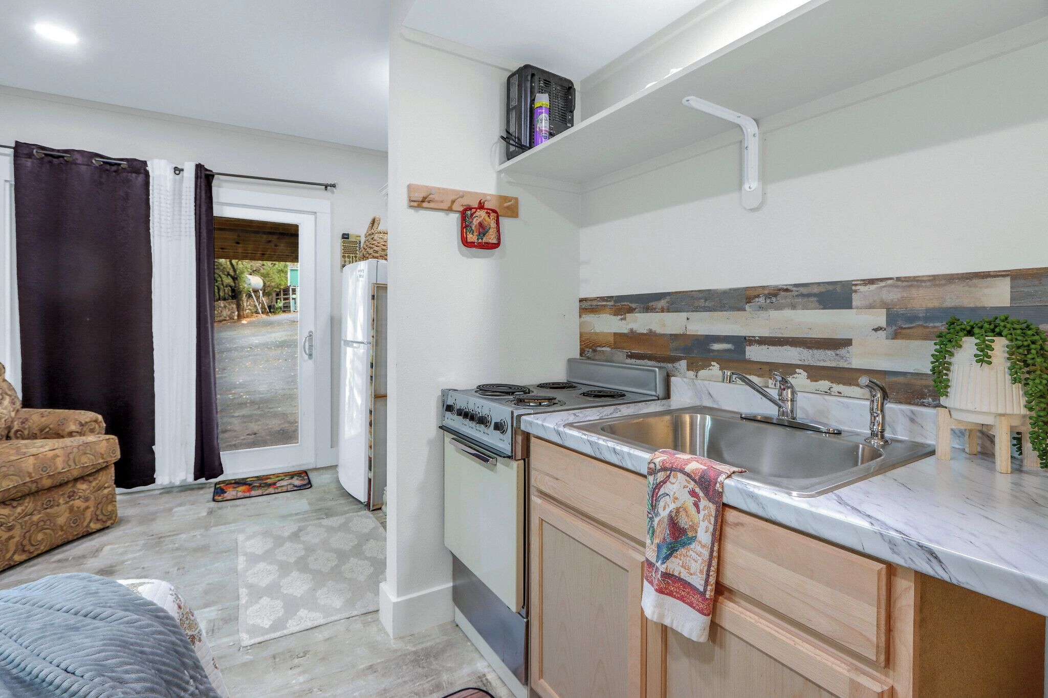 A compact kitchen with a stove, sink, and wooden cabinets.