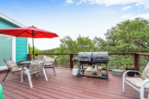 A wooden deck with outdoor furniture, a grill, and a red umbrella. - The Coop at Canyon Lake I Pool & Ideal for Families (Canyon Lake)