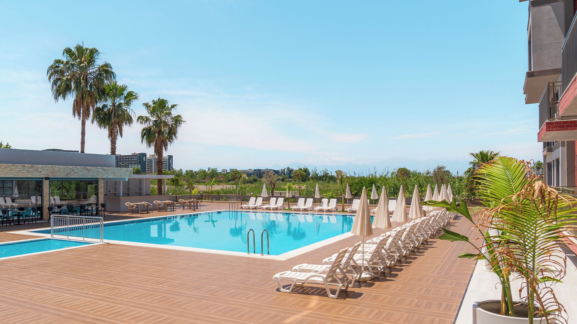 A pool area with lounge chairs and palm trees.