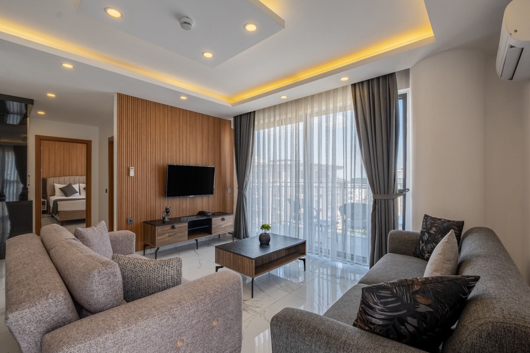 A modern living room with a sofa, a coffee table, a TV, and a wooden panel wall.