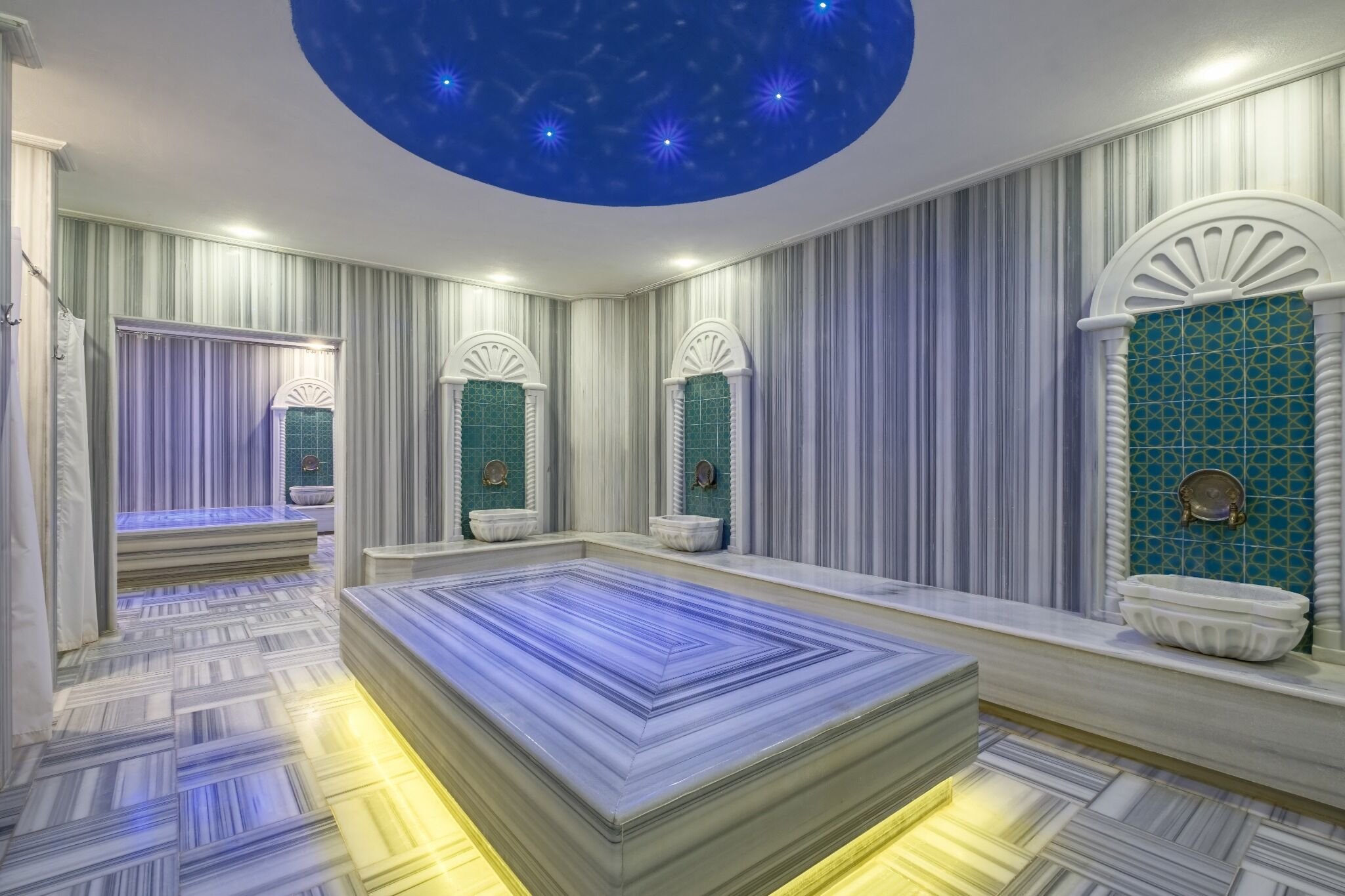 A room with a large bed, a ceiling with a starry design, and a wall with a green tile pattern.