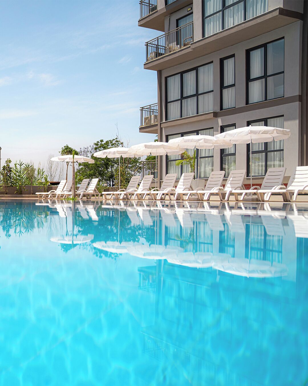 Een modern hotel met een zwembad, ligbedden en parasols.