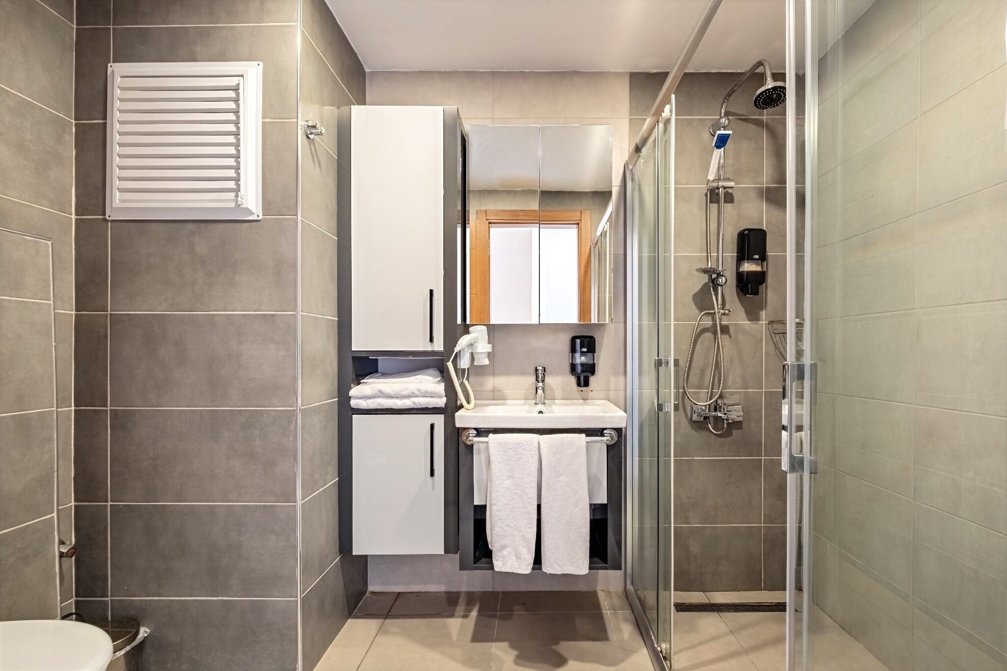 A modern bathroom with a shower, toilet, and sink.