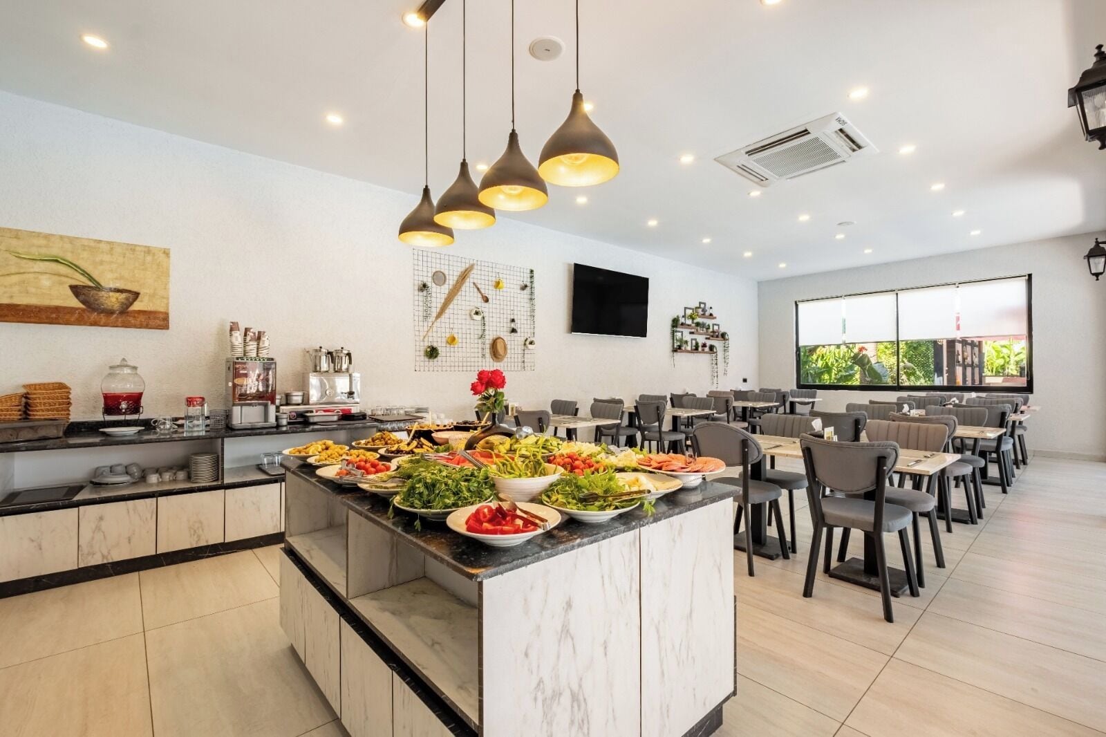 Un comedor moderno con una isla central repleta de productos frescos, rodeado de mesas y sillas para comer.