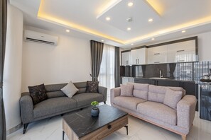 A modern living room with two sofas, a coffee table, and a kitchen area with cabinets and a countertop. - Laristone Suite Spa Hotel (Antalya)