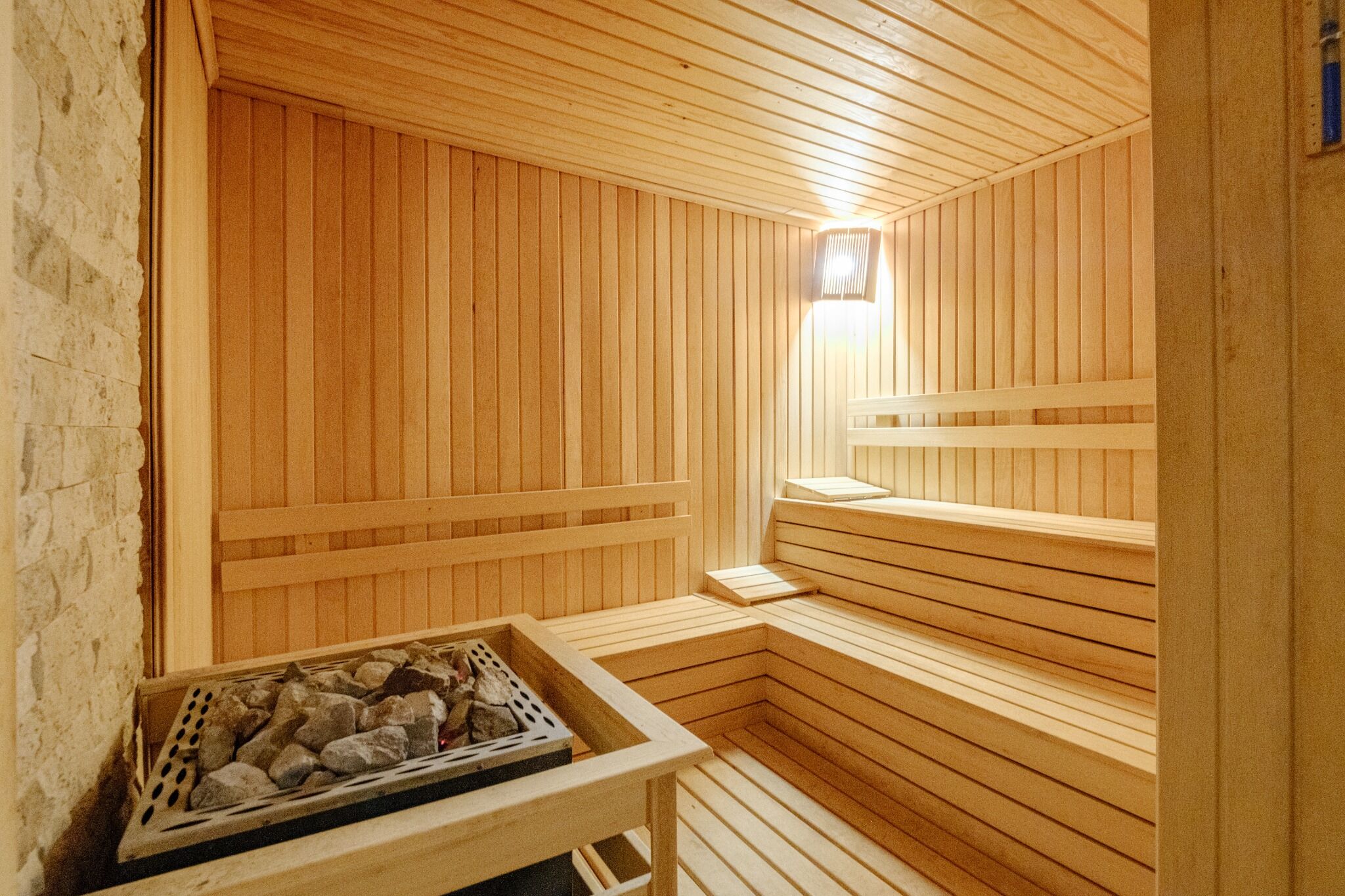 Eine Holzsauna mit Bänken und einem Steinkorb.