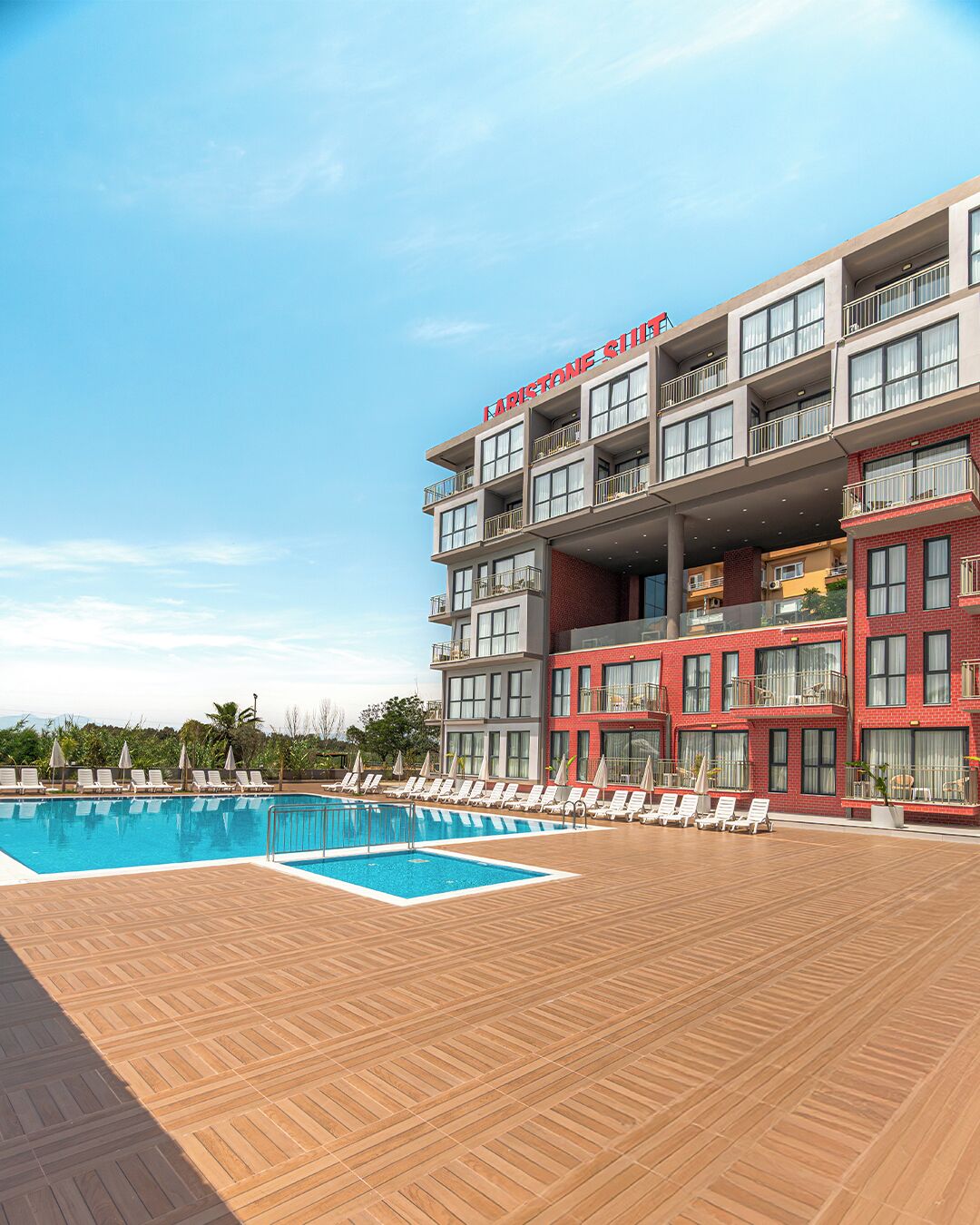 A hotel with a swimming pool, multiple balconies, and a wooden deck area.