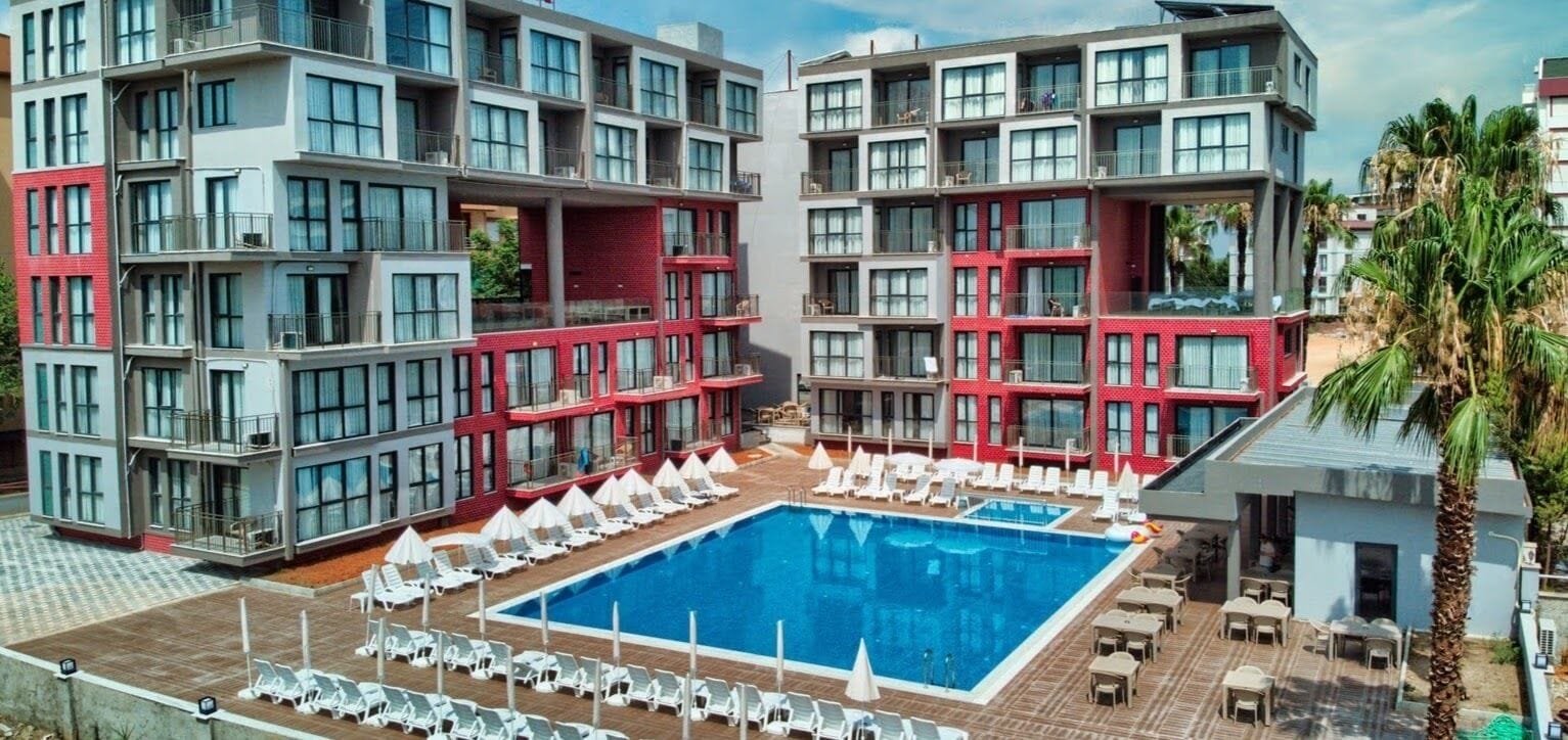 A modern hotel with a central swimming pool surrounded by sun loungers and a deck area.