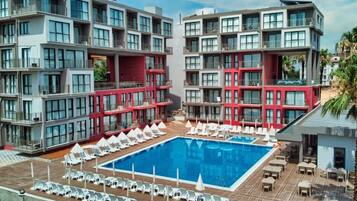 A modern hotel with a central swimming pool surrounded by sun loungers and a deck area.
