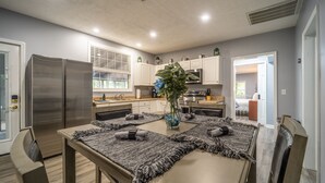 Una cocina moderna con una mesa de comedor, sillas y un refrigerador.