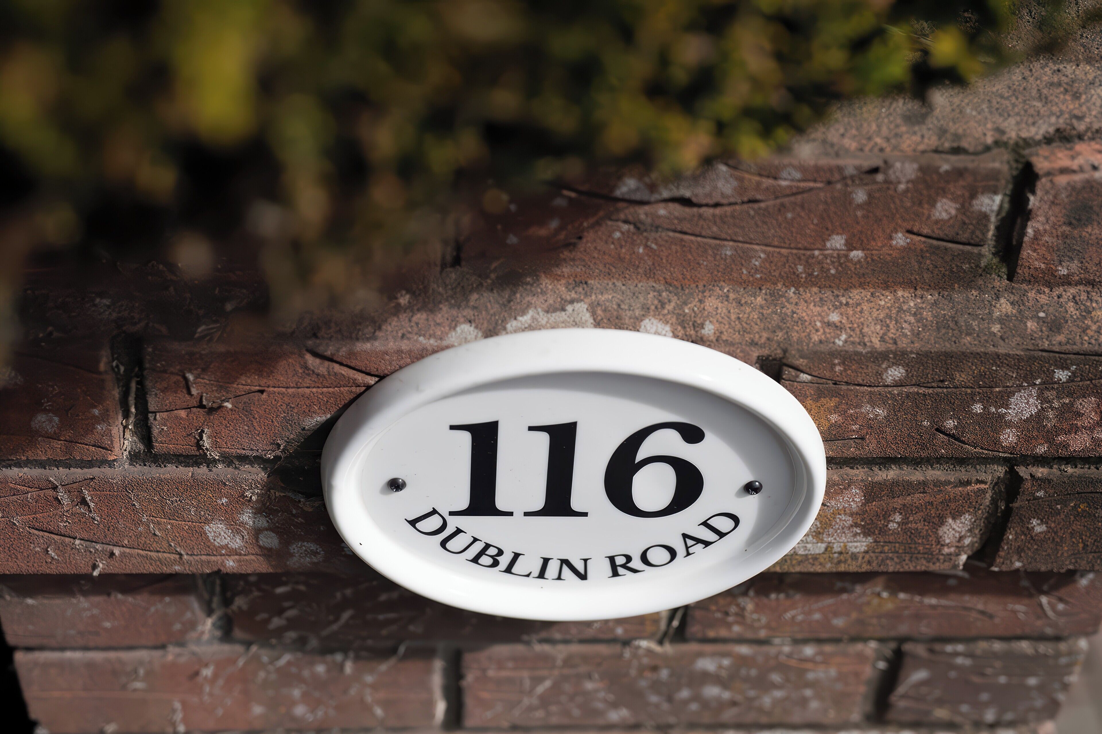 A house number plaque on a brick wall.
