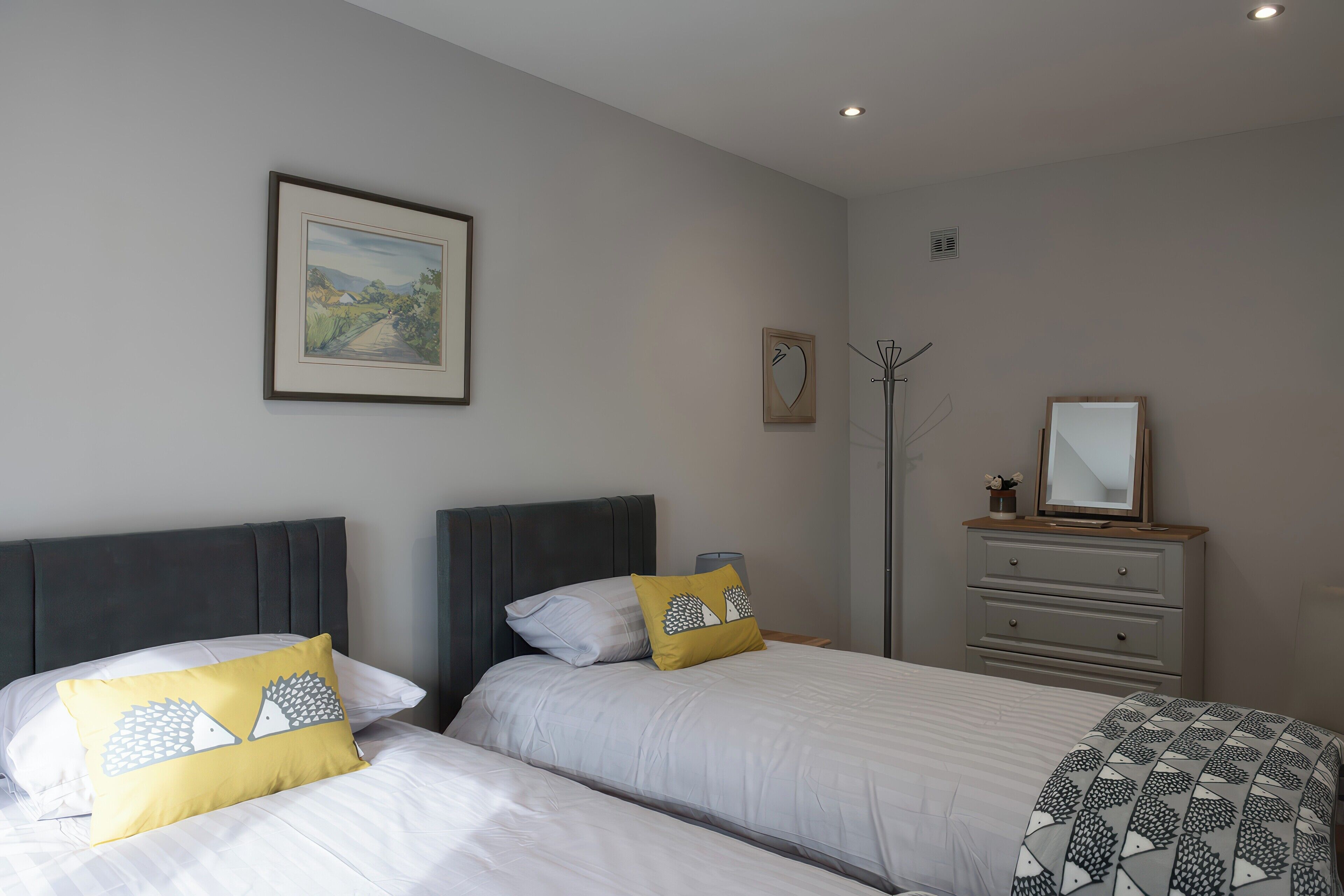 A bedroom with two beds, a dresser, a mirror, and a framed picture on the wall.