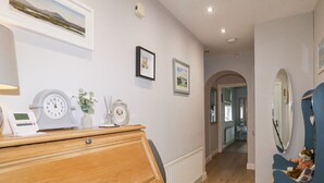 A room with a wooden dresser, a clock, a small plant, and framed pictures on the wall. - Shirley's House (Omagh)
