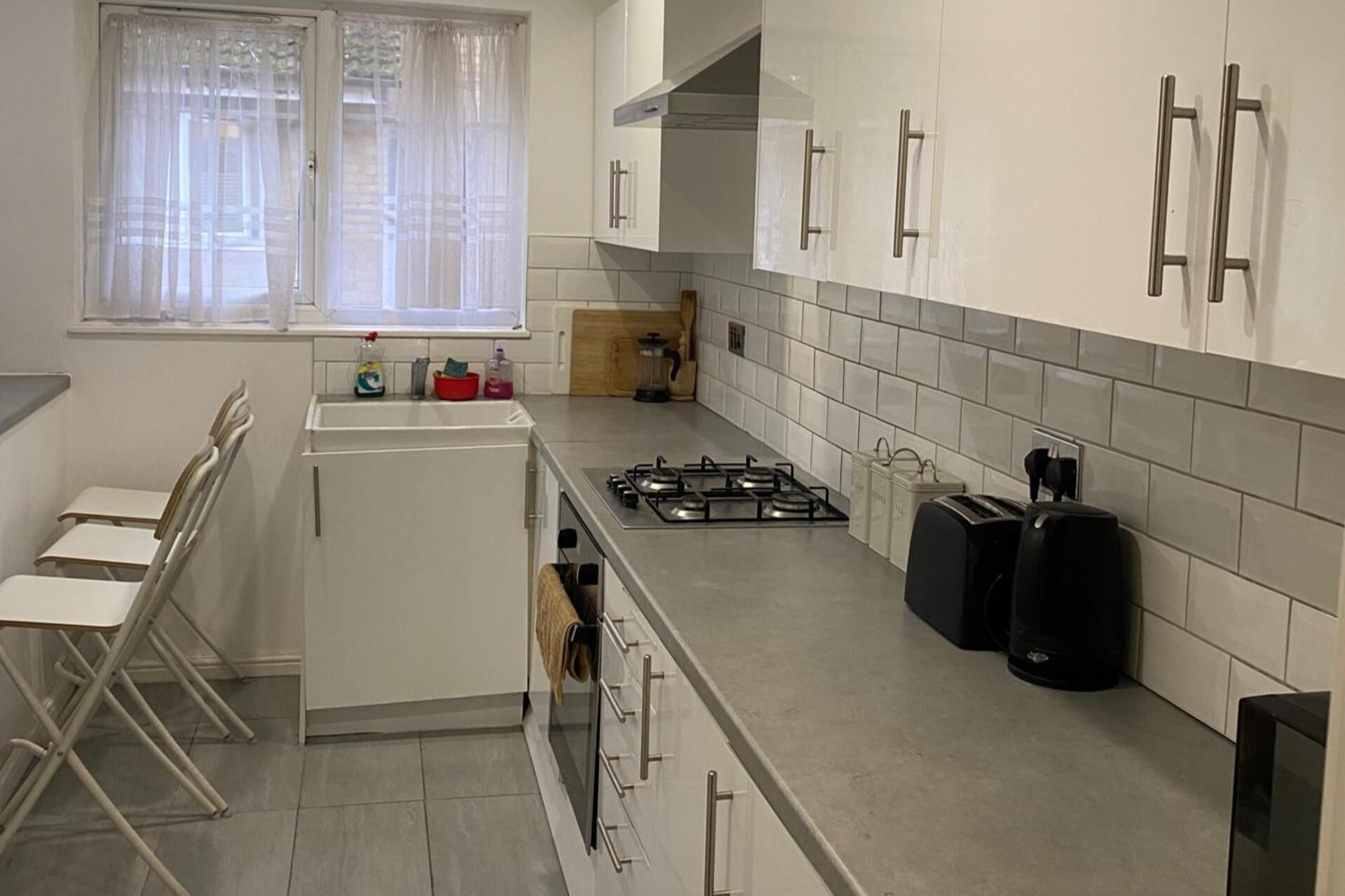 Una cocina con armarios blancos, una estufa a gas, un tostador y una cafetera.