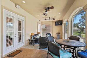 A covered patio with a ceiling fan, outdoor seating, and a view of the outdoors. - Mediterranean Home with Club Amenities & Golf Cart (Destin)