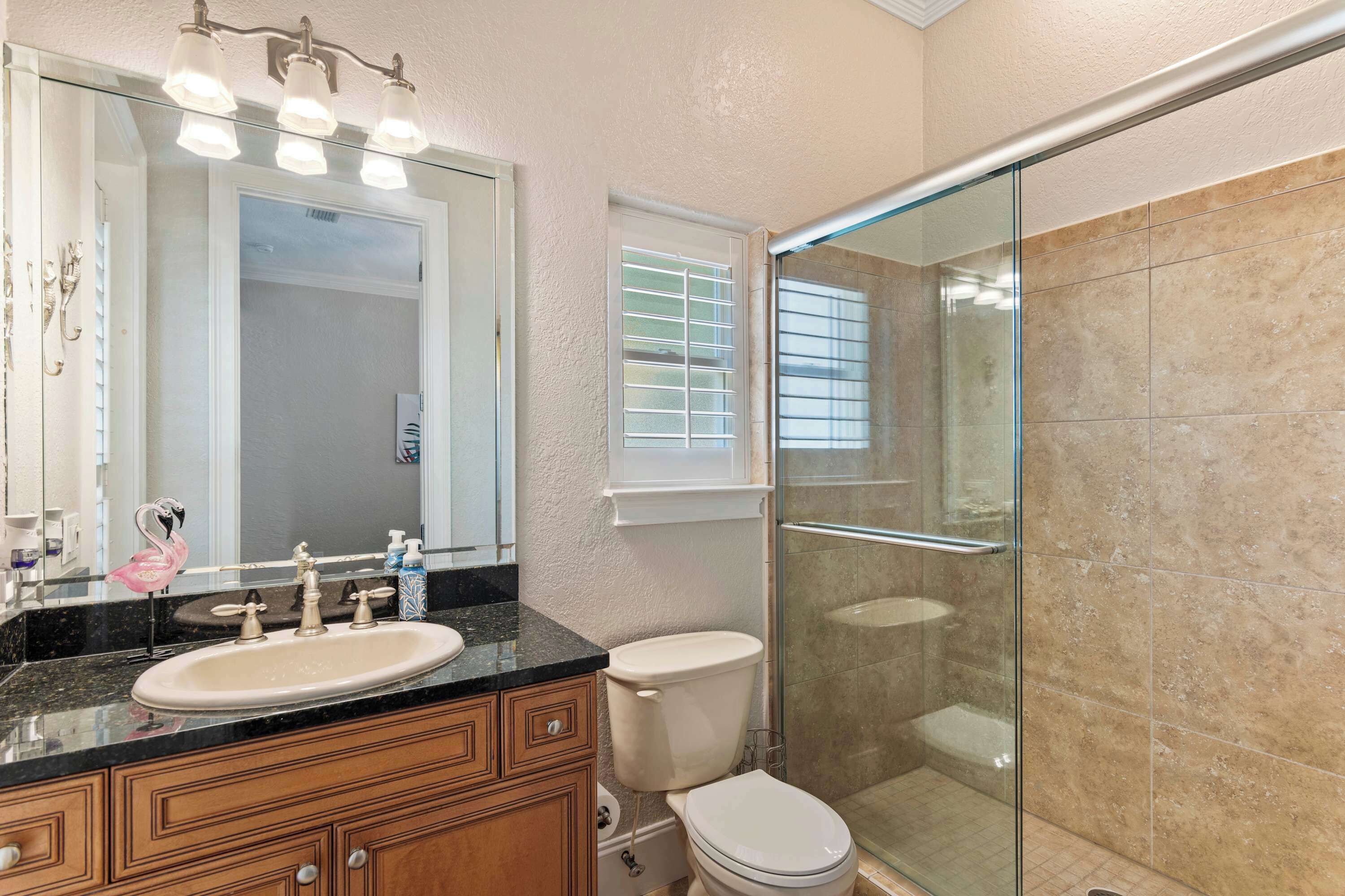 A bathroom with a glass shower enclosure, a sink with a vanity, and a toilet.