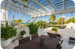 Eine Terrasse im Freien mit Holztisch, Bänken und einer Pergola.