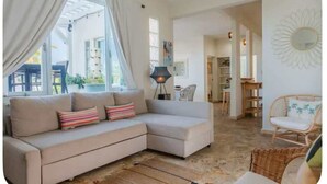 A living room with a beige sectional sofa, a wicker chair, and a floor lamp.