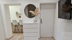 A bedroom with two beds, a dresser, a round mirror, and a TV on the wall.