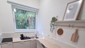 A modern kitchen with white cabinets, a wooden countertop, a sink, and a window with a view of greenery.