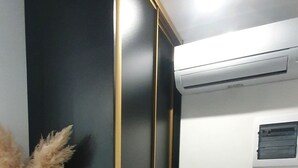A room with a black wardrobe, a white wall with a small window, and a wooden floor. - Balance Deluxe Studio Koper (Koper)