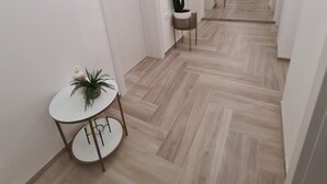 A modern hallway with a wooden floor, white walls, and minimalist decor including a cactus, a small table with a plant, and a sign offering free Wi-Fi. - Balance Deluxe Studio Koper (Koper)
