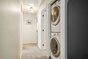 A laundry room with two front-loading washing machines, a door leading to another room, and a light fixture on the ceiling. - Summer Escape (Wells)