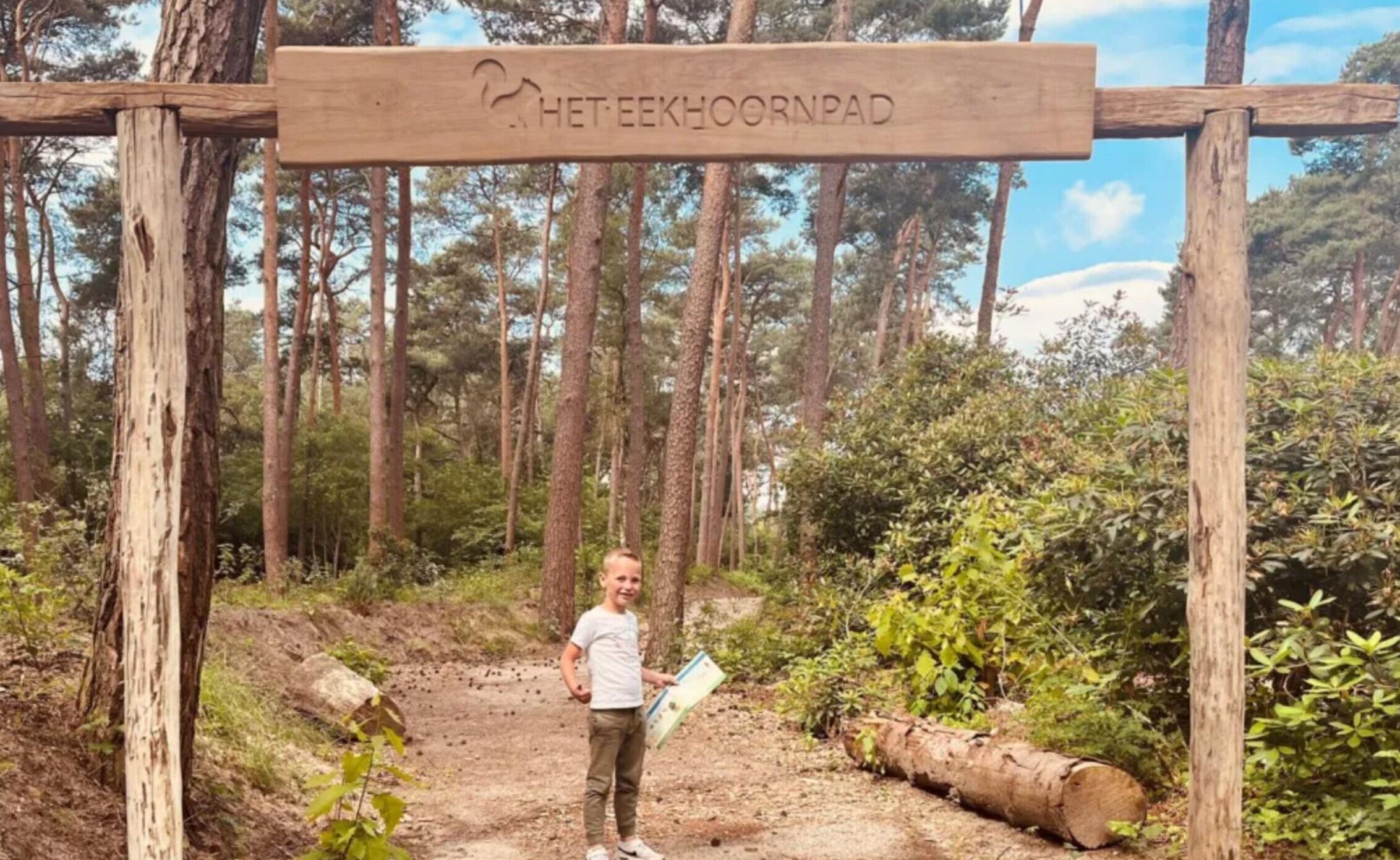 A wooden sign with the text 'HETTE EEKHOORNPAD' in a forested area.