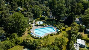 An aerial view of a residential area with a swimming pool surrounded by trees and houses.