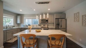 A modern kitchen with a large island, stainless steel appliances, pendant lighting, and a view to the outdoors. - Airy 3B2.5B Nest in Central Seattle/ AC / Parking (Seattle)