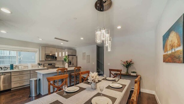 A modern kitchen with stainless steel appliances, a dining area with a long table set for six, and a large window providing natural light. - Airy 3B2.5B Nest in Central Seattle/ AC / Parking (Seattle)