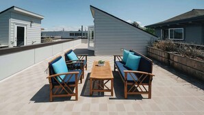 A rooftop patio with wooden furniture and a view of neighboring buildings. - Airy 3B2.5B Nest in Central Seattle/ AC / Parking (Seattle)