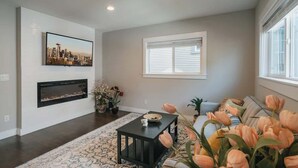 A living room with a fireplace, a large window with blinds, a sofa, and a coffee table. - Airy 3B2.5B Nest in Central Seattle/ AC / Parking (Seattle)