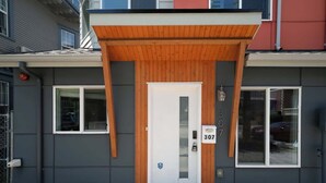 A modern building with a grey facade, a wooden entrance canopy, and a white door with the number 307. - Airy 3B2.5B Nest in Central Seattle/ AC / Parking (Seattle)