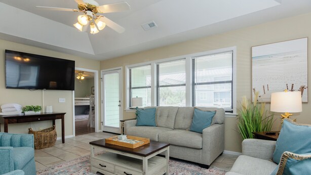 A living room with a sofa, a coffee table, a TV, and a ceiling fan.