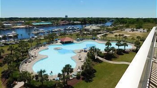 Un resort con una piscina central grande, varias piscinas más pequeñas y un puerto deportivo con barcos.
