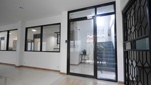 Ein Korridor mit Glastüren und -fenstern, einem Fliesenboden und einem Feuerlöscher an der Wand.