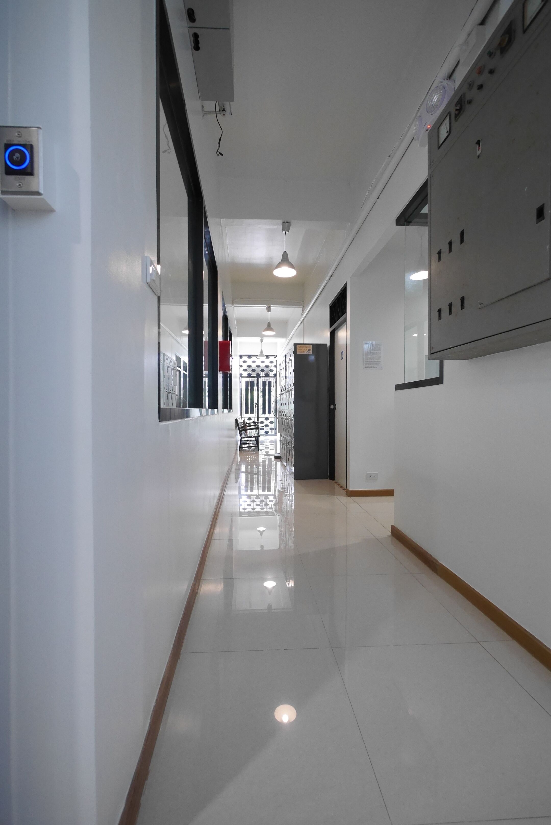 A clean, modern hallway with a shiny floor, a security camera, and a fire alarm on the wall.