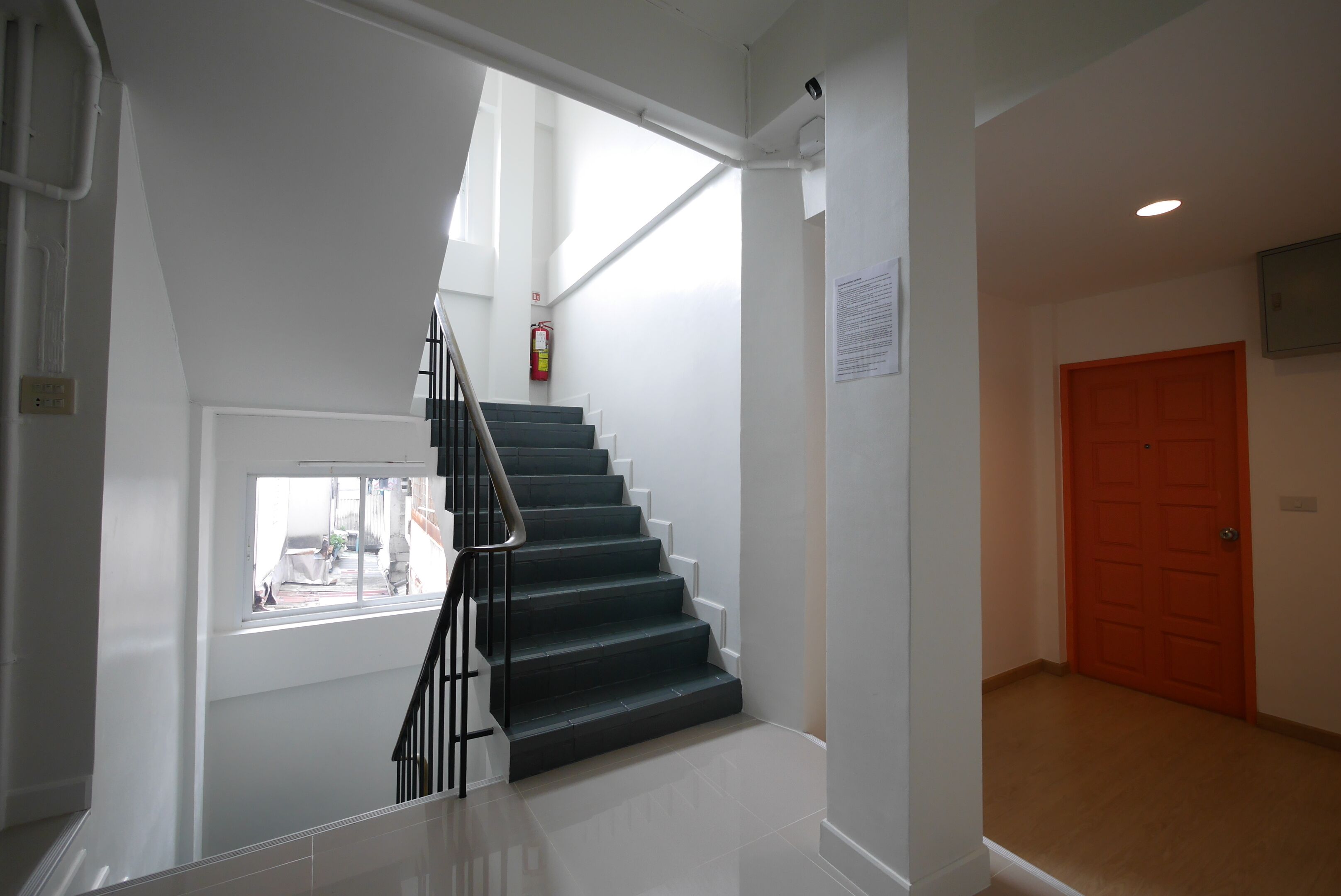 A staircase with a handrail, a window, and a door in a hallway.
