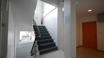 A staircase with a handrail, a window, and a door in a hallway.