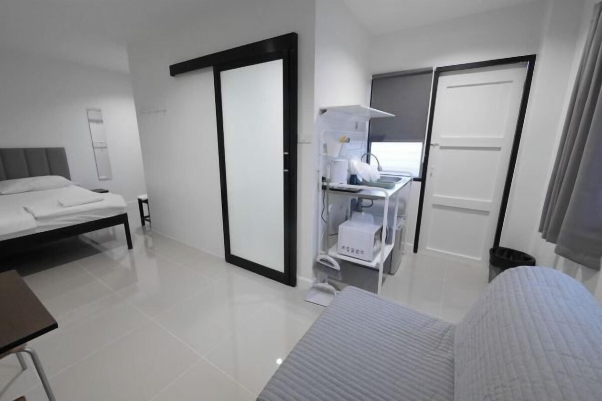 A modern hotel room with a bed, a desk, and a wardrobe.