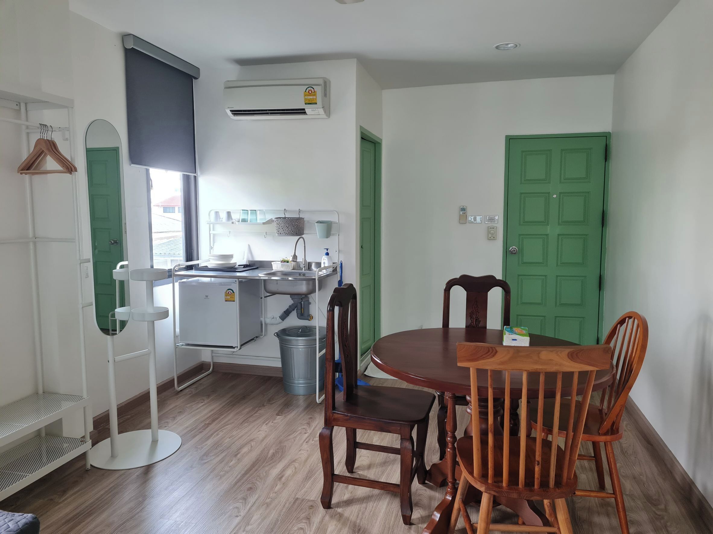A compact kitchen with a sink, a small refrigerator, and a green door.