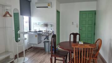 A compact kitchen with a sink, a small refrigerator, and a green door.