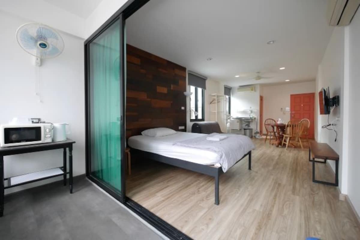 A modern bedroom with a bed, a desk, a chair, and a dining area.