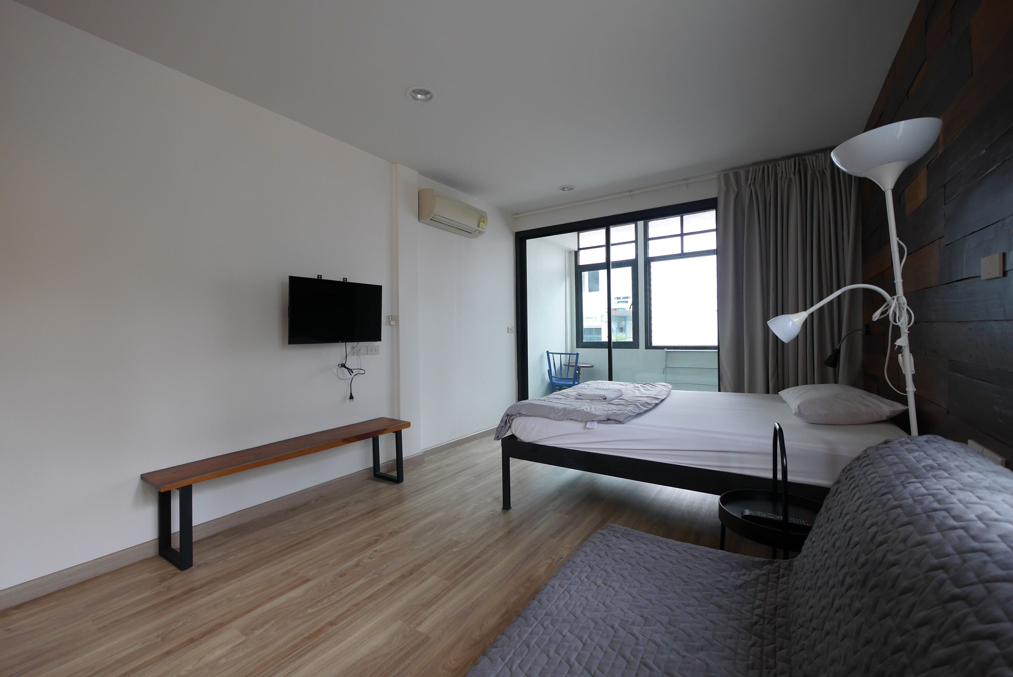 A modern bedroom with a bed, bench, and a TV mounted on the wall.