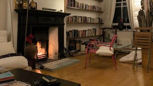 A living room with a fireplace, bookshelves, a mirror, and a chandelier.