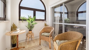 Un balcone accogliente con mobili in vimini, una pianta in vaso e vista sulla città.