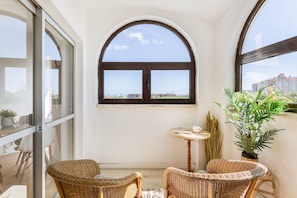 Ein Balkon mit Korbstühlen, einem kleinen Tisch und einem Blumentopf.