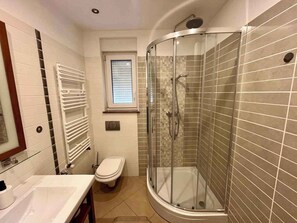 Une salle de bain moderne dotée d’une douche à parois de verre, de toilettes et d’un lavabo.